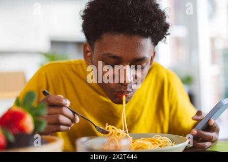 Adolescente che mangia spaghetti a casa Foto Stock