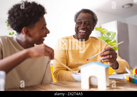 Allegro nonno che dipinge la casa modello con il nipote a casa Foto Stock