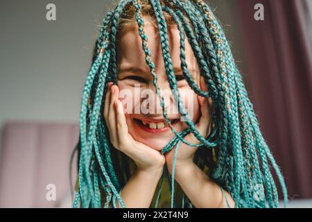 Ragazza felice con capelli trecciati tinti turchesi a casa Foto Stock