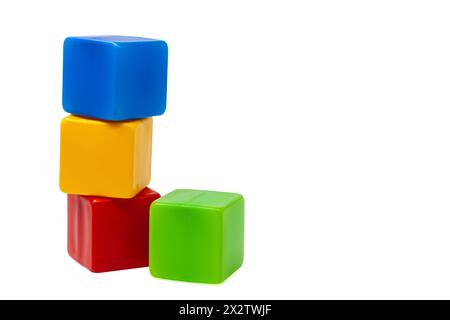 Cubi di plastica multicolore per giochi per bambini. Il cubo giallo si trova sopra il cubo rosso e blu, accanto al cubo verde. Uno contro uno. Foto Stock