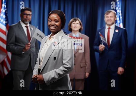 Felice giovane leader politico afro-americana donna in abbigliamento formale che guarda la telecamera mentre partecipa alle elezioni presidenziali Foto Stock