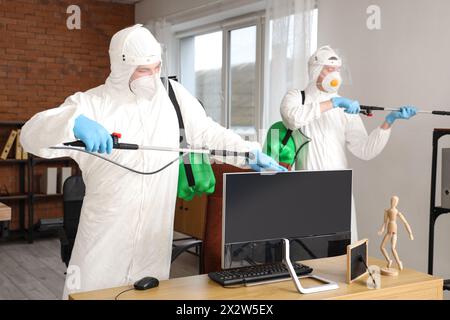 Lavoratore professionista che disinfetta il monitor del computer in ufficio Foto Stock