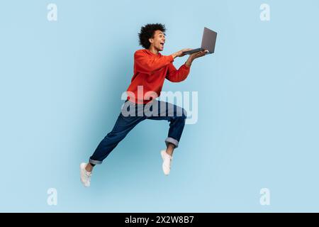 Uomo giocoso che salta con un notebook in mano Foto Stock