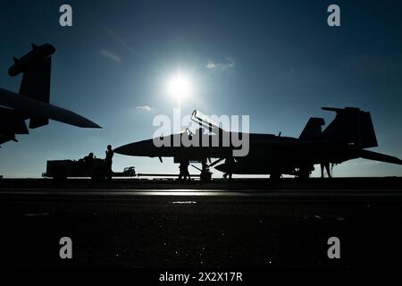 USS Theodore Roosevelt, Stati Uniti. 22 aprile 2024. I marinai della US Navy trainano un F/A-18E Super Hornet dal Fist of the Fleet of Strike Fighter Squadron 25, sul ponte di volo della portaerei classe Nimitz USS Theodore Roosevelt in corso di operazioni di routine, il 22 aprile 2024, sul Mar delle Filippine. Crediti: MCS Aaron Haro Gonzalez/US Navy Photo/Alamy Live News Foto Stock