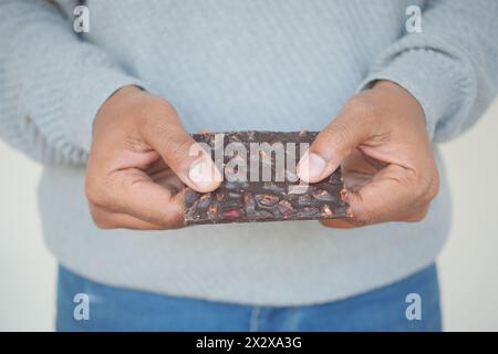 uomo che regge a mano un cioccolato fondente con noci miste Foto Stock