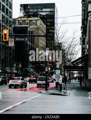 Vancouver, Canada - febbraio 28 2024: Una foto dell'incrocio tra Burrard e Georgia Street in una mattina piovosa con auto in strada e persone in attesa Foto Stock