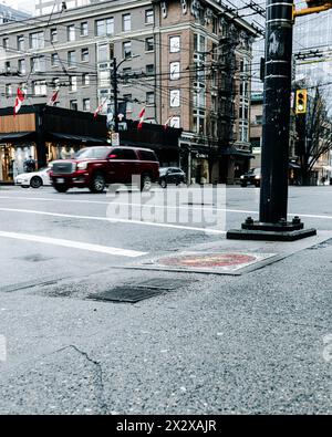 Vancouver, Canada - febbraio 28 2024: Una foto dell'incrocio tra Burrard e Robson Street con le auto che passano e uno scarico di vapore sul marciapiede nel Foto Stock