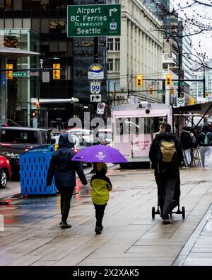 Vancouver, Canada - febbraio 28 2024: Un bambino piccolo con un ombrello viola che cammina accanto ai suoi genitori sulla piazza della Vancouver Art Gallery Foto Stock