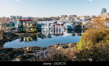 Victoria, Canada - 17 marzo 2024: Una fila di case galleggianti colorate al Fisherman's Wharf, che catturano la splendida luce del sole riflessa dal mare. Foto Stock