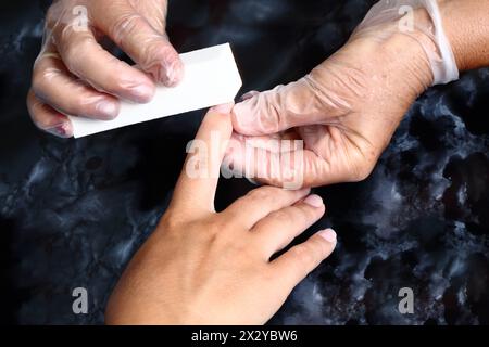 Il maestro lucida le unghie durante una manicure nel salone Foto Stock