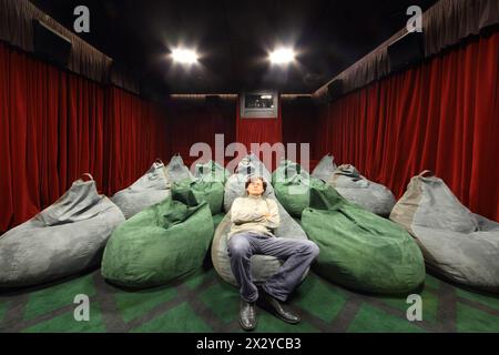 L'uomo guarda i film comodamente seduto in un piccolo cinema. Foto Stock