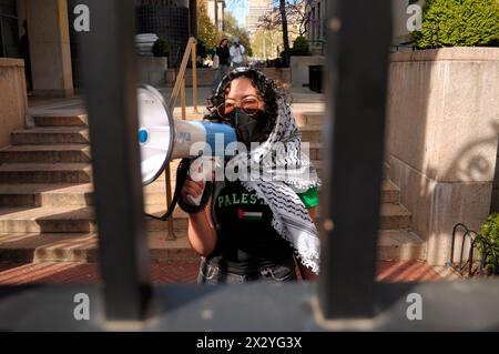 Un manifestante pro-Palestina partecipa a una protesta, cantando slogan su un megafono dall'interno di un ingresso alla Columbia University. I manifestanti pro-palestinesi si sono riuniti in uno degli ingressi della Columbia University di Manhattan, New York, condannando le operazioni militari delle forze di difesa israeliane a Gaza. Dalla scorsa settimana, studenti e attivisti filo-palestinesi all'interno dell'università hanno organizzato una protesta sit-in sul prato, formando un "accampamento di solidarietà di Gaza”. Gli studenti di altre università hanno formato accampamenti simili nei campus a livello nazionale a sostegno della Palestina. Dalla guerra st Foto Stock