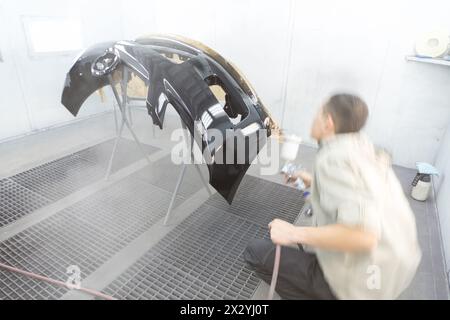 Il pittore dipinge un autoscontri presso l'officina di riparazione Foto Stock