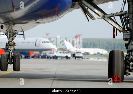 Vista in aeroporto da sotto l'ala del piano in piedi su parcheggio Foto Stock