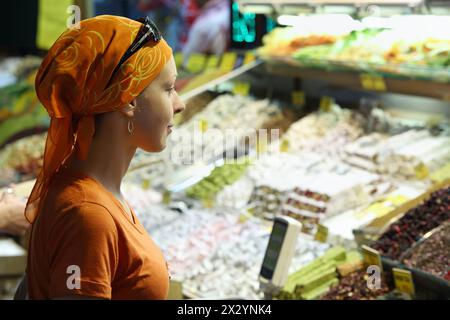 Beautiful Woman guarda i prodotti (frutta secca e spezie) nel mercato dell'Asia centrale. Foto Stock