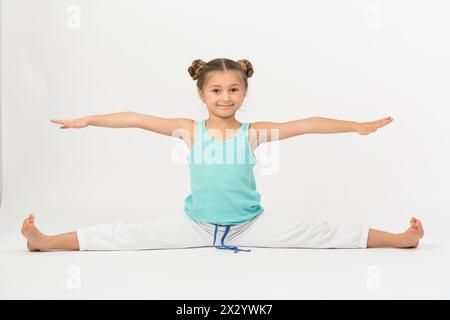 Una ragazza fa esercizio ginnico seduto su fessure e facendo le mani in direzioni diverse Foto Stock