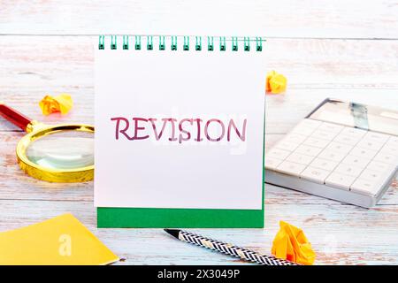 Concetto di business. Parola di REVISIONE in un quaderno accanto a una calcolatrice, una lente d'ingrandimento, una matita e una carta arricciata Foto Stock