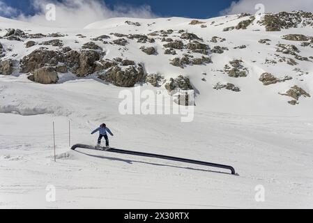 Trucchi per lo Snow Park in montagna. Trucchi per la pipa dello Snow Park. Snowboarder nel parco su un pipex. Jibbing invernale nello snwopark delle Alpi. Snow Park sulle alpi. Foto Stock