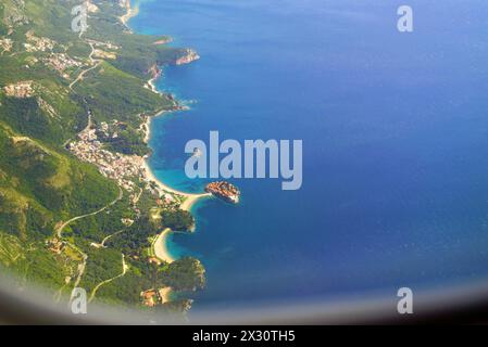 Vista dalla finestra dell'aeroplano della famosa isola di Sveti Stefan in Montenegro e della pittoresca costa accanto ad essa Foto Stock