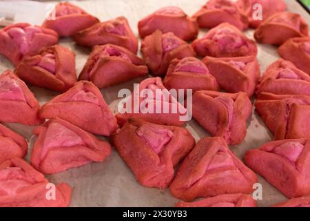 Hamantashen rosa appena sfornato, biscotti triangolari ripieni di cioccolato o marmellata, tradizionalmente consumati dagli ebrei durante la celebrazione di Purim. Foto Stock