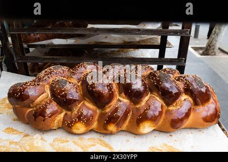 Grande pagnotta di Challah appena sfornata, intrecciata o pane all'uovo in vendita in una panetteria di Gerusalemme alla vigilia del sabato ebraico. Foto Stock