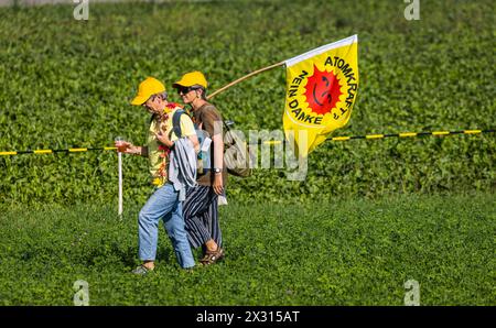 Zwei Anti-Atomdemonstrantinnen mit der bekannten Flagge der Atomkraftgegner laufen über eine saftig, Grüne Wiese. (Marthalen, Schweiz, 30.08.2022) Foto Stock