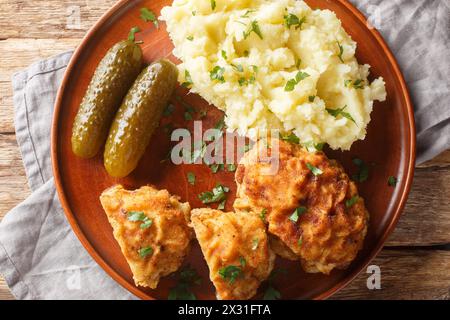 Polpetta di maiale ceca Holandsky rizek con formaggio, impanata, servita con purè di patate e sottaceto da vicino in un piatto sul tavolo. Via superiore orizzontale Foto Stock