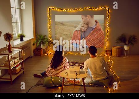 Coppia che si gode San Valentino, un appuntamento romantico a casa, guardando un film sul proiettore Foto Stock