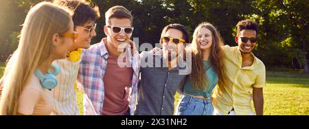 Gruppo di amici felici e spensierati che si divertono a passeggiare insieme nel parco estivo. Foto Stock