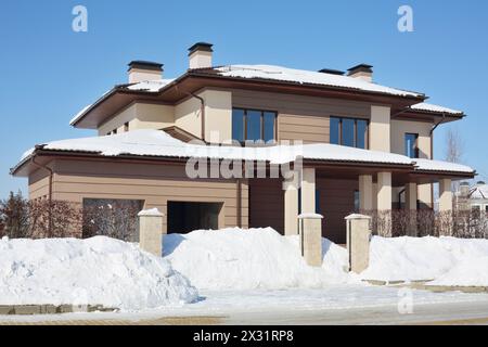 Cottage marrone semplice con garage nelle giornate invernali ghiacciate e soleggiate. Foto Stock