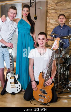 Gruppo musicale di tre ragazzi e una ragazza in Recording Studio con strumenti musicali Foto Stock