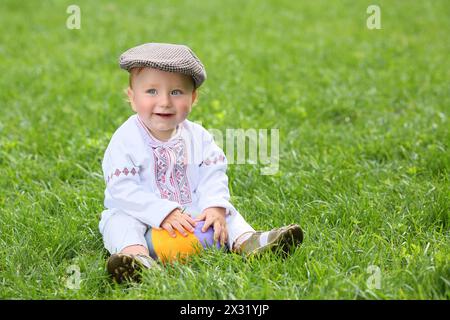 Il bambino nel costume nazionale russo che gioca con la palla sull'erba Foto Stock