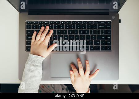 Mano del bambino sulla tastiera del computer portatile. Accesso a informazioni, protezione e usabilità Foto Stock