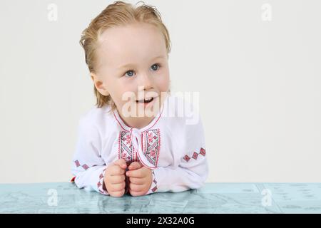 Bambino in costume nazionale russo e grande mappa su sfondo bianco. Foto Stock