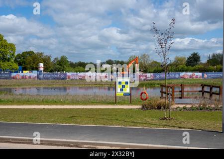 Un cartello accanto a un lago artificiale su un cantiere edile che dice che lo sviluppatore sta cercando di creare una comunità sostenibile. Foto Stock