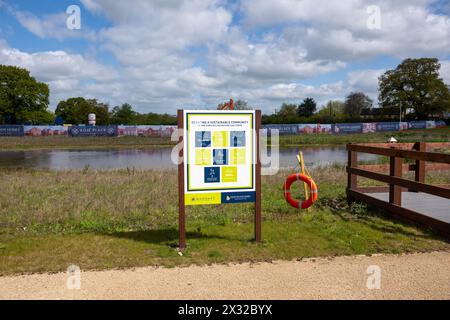 Un cartello accanto a un lago artificiale su un cantiere edile che dice che lo sviluppatore sta cercando di creare una comunità sostenibile. Foto Stock