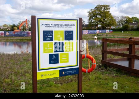 Un cartello accanto a un lago artificiale su un cantiere edile che dice che lo sviluppatore sta cercando di creare una comunità sostenibile. Foto Stock