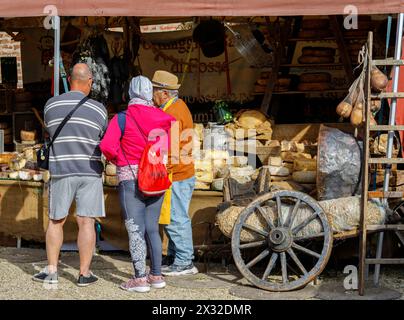 Moncalieri, Piemonte, Italia - 20 aprile 2024: Clienti di fronte a una banchina di mercato che vende formaggi artigianali e salumi. Foto Stock