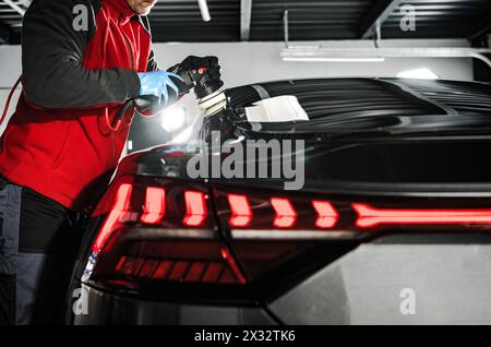 Servizio di dettaglio auto professionale. Ceretta e lucidatura della carrozzeria del veicolo all'interno di un negozio. Foto Stock