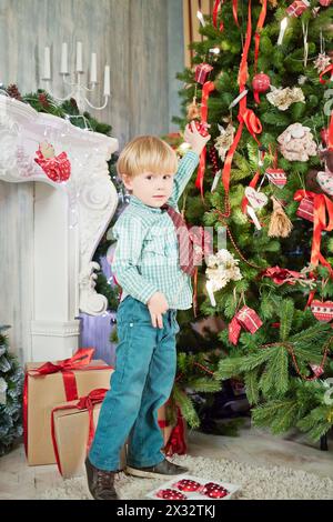 Il bambino appende la decorazione dell'albero di natale sull'albero di Natale Foto Stock