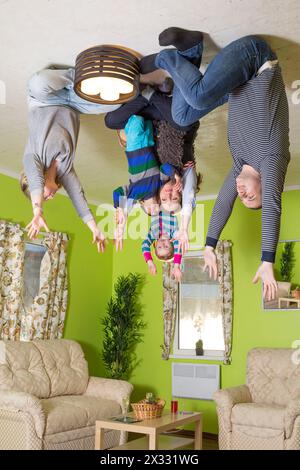 Famiglia di cinque preghiere sul soffitto capovolte in casa rovesciata Foto Stock