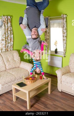 Famiglia di tre persone capovolte sul soffitto di casa invertita Foto Stock