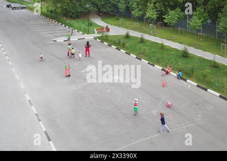 I bambini piccoli con adulti disegnano gesso colorato sul marciapiede del parco Foto Stock