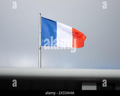 Bandiera di Francia su un edificio. Il cielo scuro è sullo sfondo. Il simbolo dell'orgoglio e del patriottismo fa parte dell'identità francese. Foto Stock