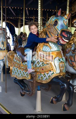 La bambina e sua madre dietro la figlia sono sedute a cavallo in giostra. Foto Stock