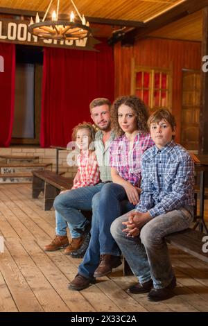 famiglia di quattro persone seduta su una panchina in un saloon Foto Stock