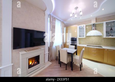 Interno di una lussuosa cucina con armadi dorati e un grande caminetto nell'appartamento Foto Stock
