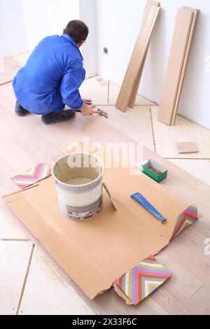 L'uomo mette il pavimento in laminato in una stanza bianca Foto Stock