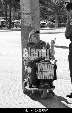 Un uomo in sedia a rotelle vende documenti all'angolo della strada Foto Stock