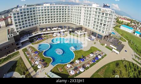 RUSSIA, SOCHI - 25 giugno 2014: I turisti si riposano intorno e nella piscina dell'hotel Radisson Blu nelle giornate di sole d'estate. Vista aerea. Foto con rumore di attio Foto Stock